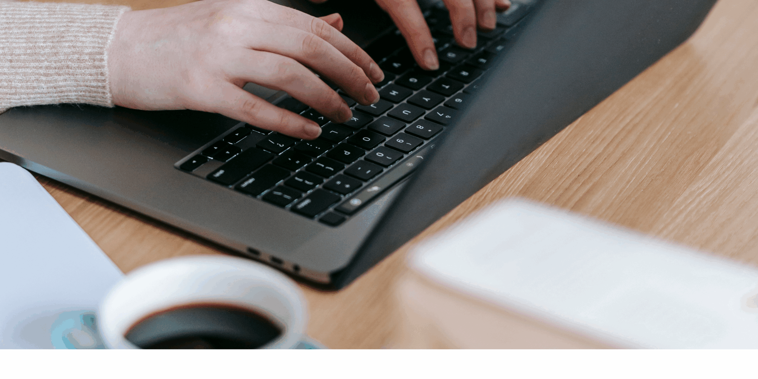 Laptop mit Kaffeetasse auf Schreibtisch – Arbeitsplatz einer Social Media Assistentin